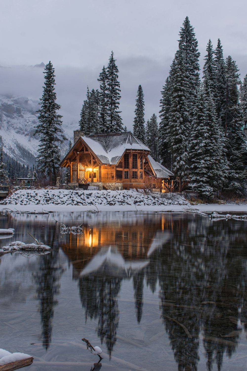 Driftwood cabin &mdash; one warm window at dusk by the water